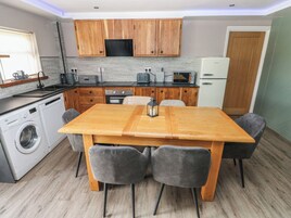 Cocina compacta con armarios de madera, horno microondas integrado y lavadora.