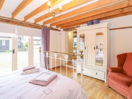 Un dormitorio con una cama, un armario, una silla roja y un balcón.