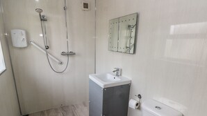 A bathroom with a shower, sink, toilet, and a mirror. - Barn Cottage (Laugharne)
