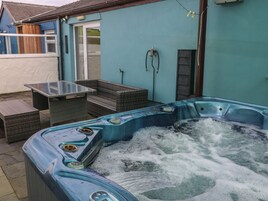 Un jacuzzi con panel de control, rodeado de muebles de mimbre y una mesa de vidrio.