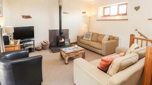 A cozy living room with a fireplace, a sofa, a TV, and a wooden coffee table. - Swallow's Nest (Penrith)