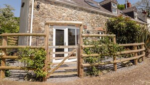 A stone building with a wooden gate, a window, and a chimney. - The Coach House (Haverfordwest)