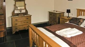 A bedroom with a wooden bed, a nightstand, a dresser, and a mirror.