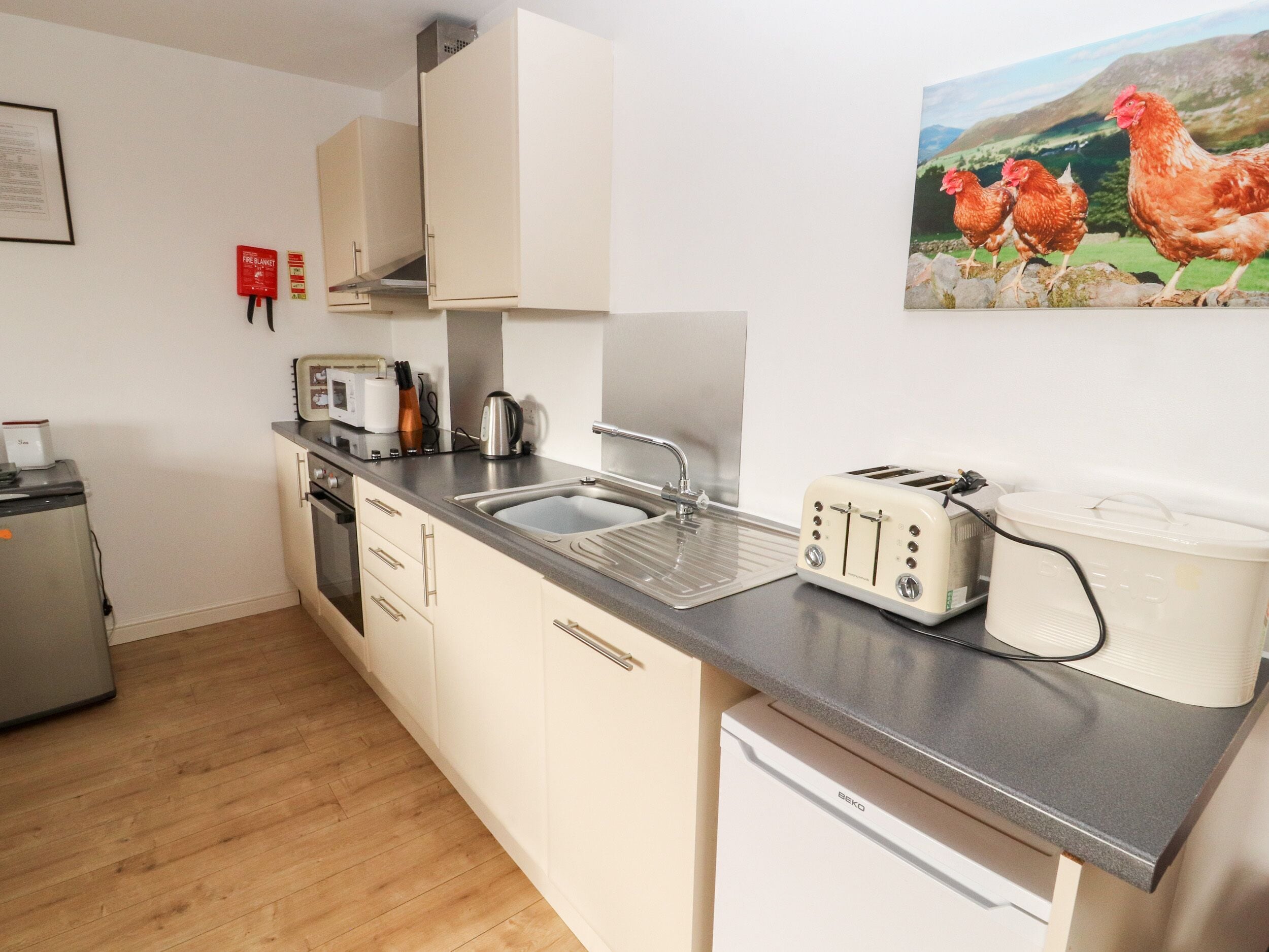 A kitchen with a sink, a toaster, a kettle, and a refrigerator.