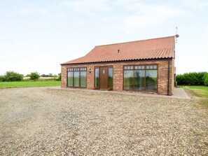 A single-story brick building with a tiled roof, large windows, and a gravel driveway. - Owl Cottage (Hull)