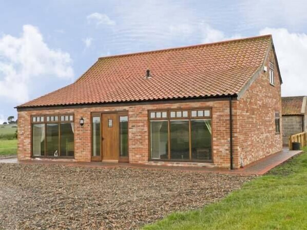 A single-story brick building with a tiled roof, large windows, and a door. - Owl Cottage (Hull)