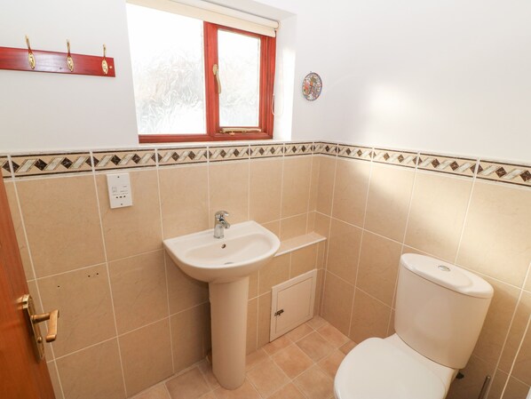A bathroom with a sink, toilet, and a window. - Min Y Traeth (Criccieth)