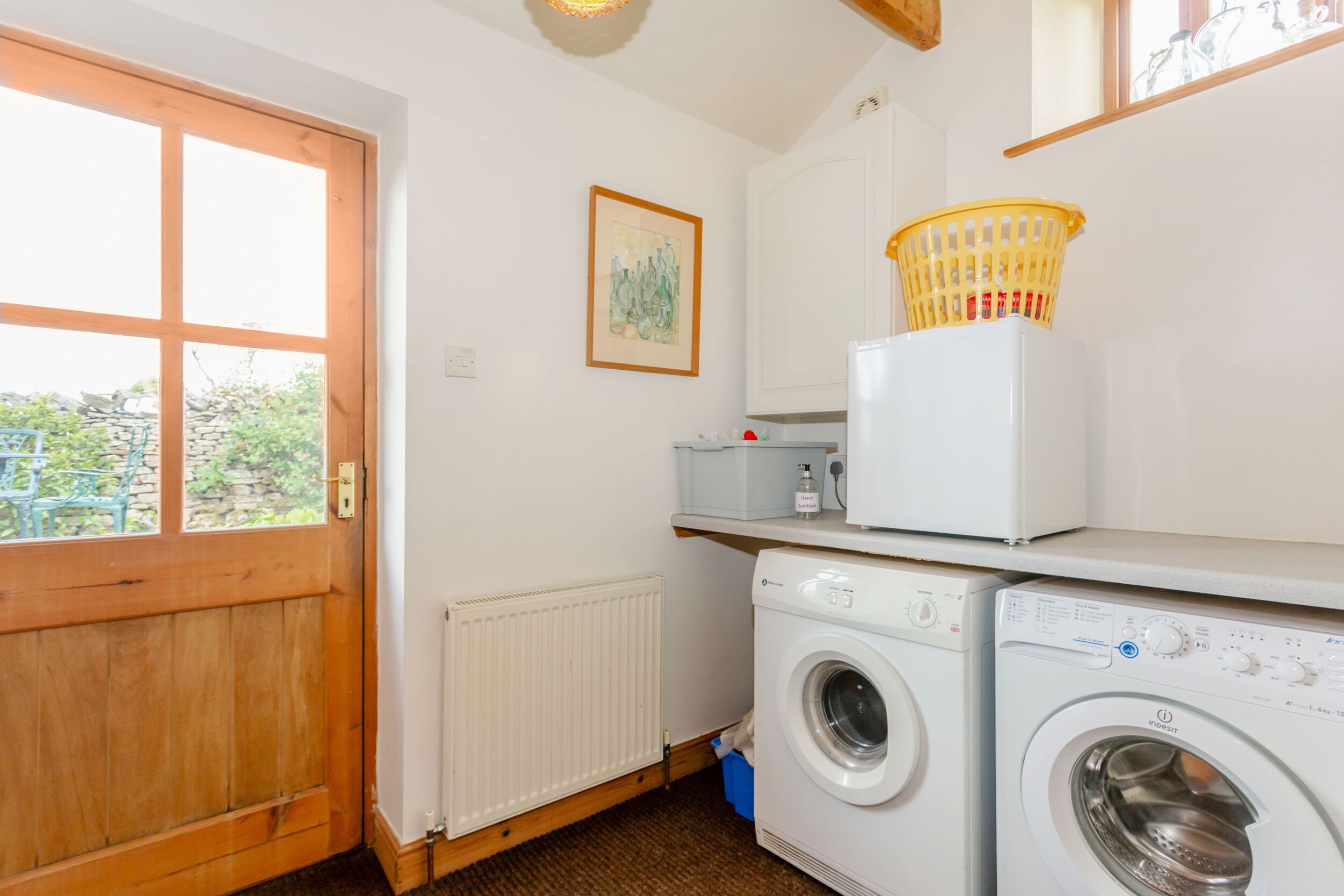 A laundry area with a washing machine, dryer, and a basket on top of the dryer.