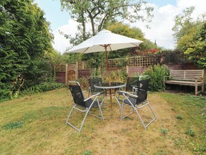 A patio with a table and chairs, an umbrella, and a wooden bench. - The Orchard (Kendal)