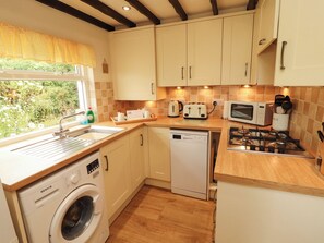 A compact kitchen with a washing machine, a microwave, a toaster, and a gas stove.