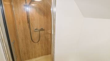 Ducha con puerta de madera y mampara de vidrio.