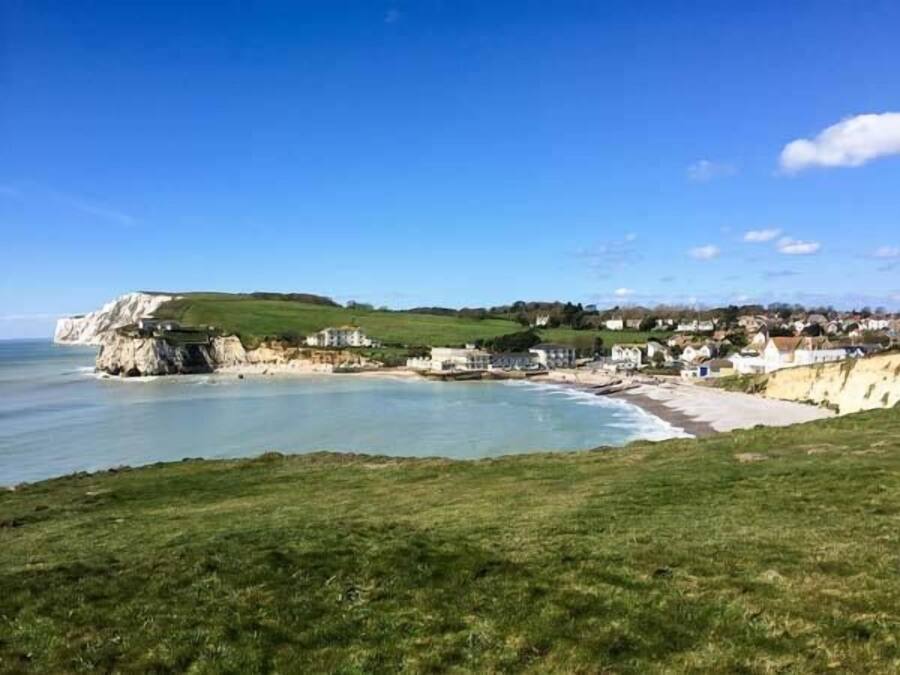 Un pueblo costero con playa, casas y acantilados.