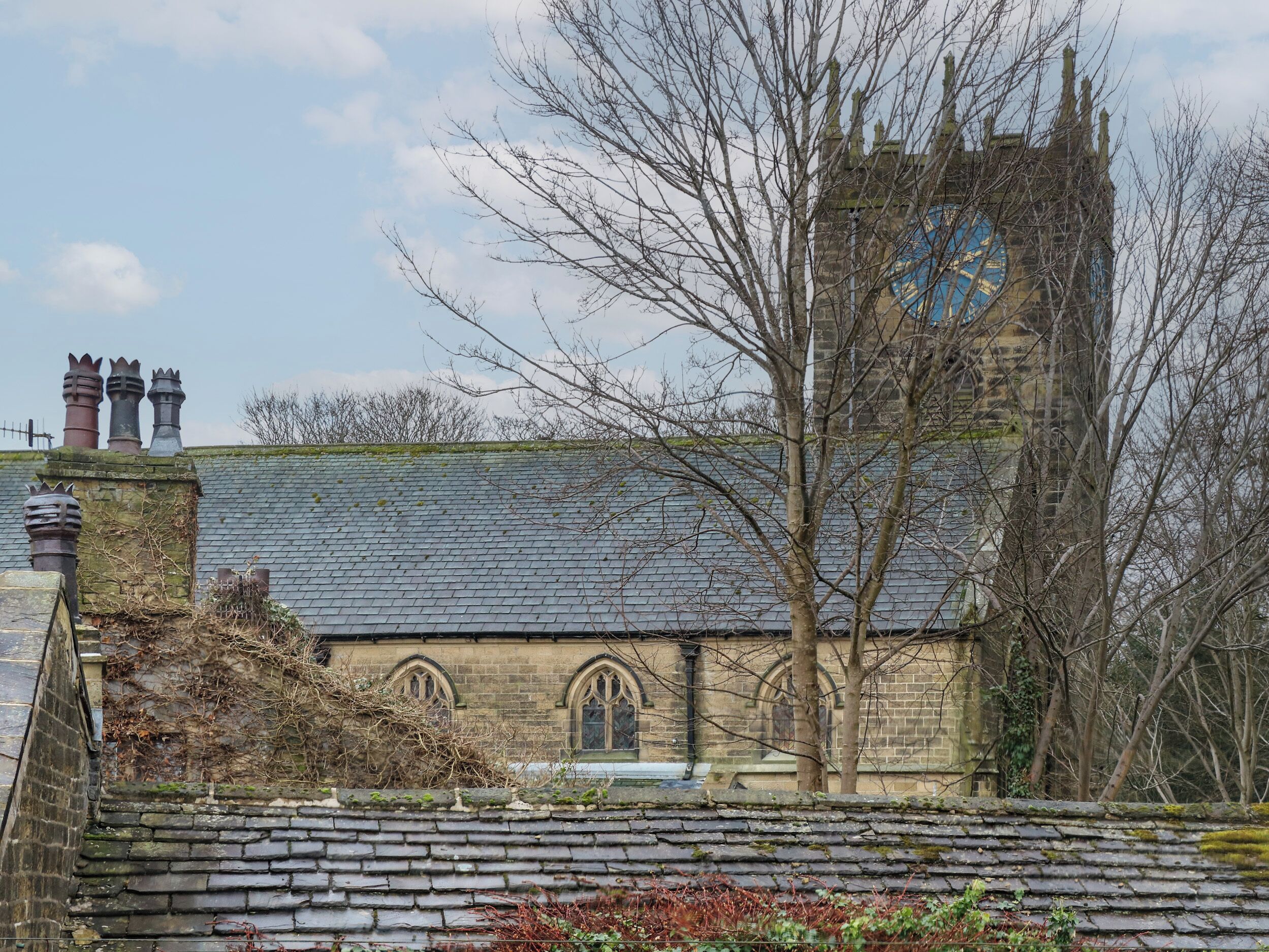 A historic church with a slate roof, arched windows, and a clock tower.