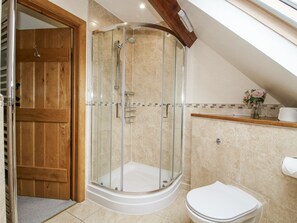 A modern bathroom with a glass-enclosed shower, a wooden door, and a white toilet. - The Milking Parlour (Craven Arms)