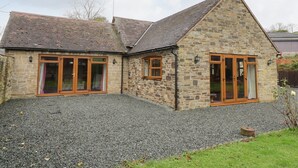 A stone house with a gravel driveway and wooden-framed windows. - The Stable (Craven Arms)