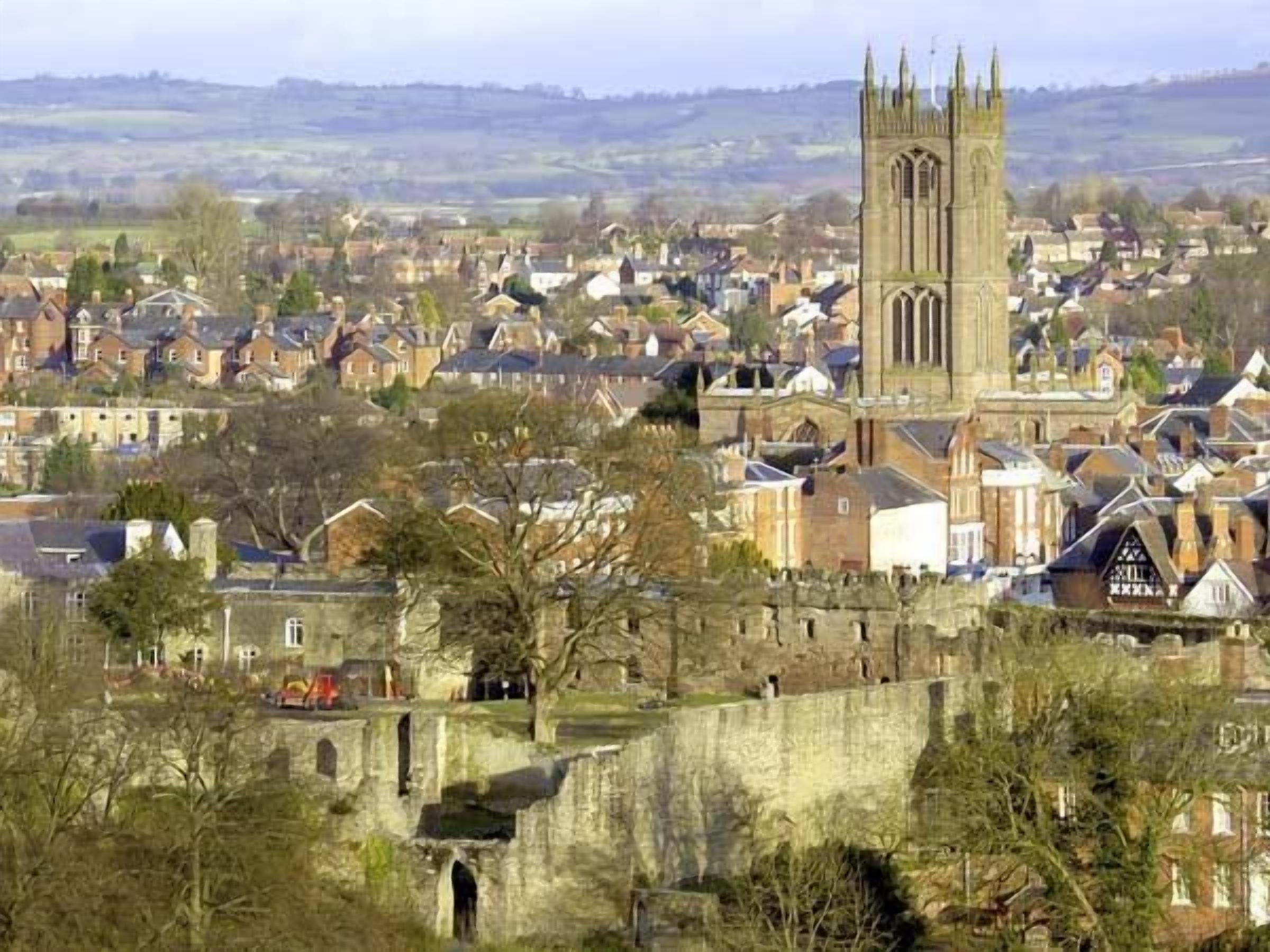 A historic town with a prominent church tower, stone walls, and traditional buildings.