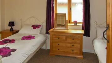 A bedroom with a bed, wooden dresser, and a nightstand.