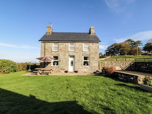 A stone house with a well-maintained lawn, a wooden bench, and a stone wall. - Tyddyn (Dyffryn Ardudwy)