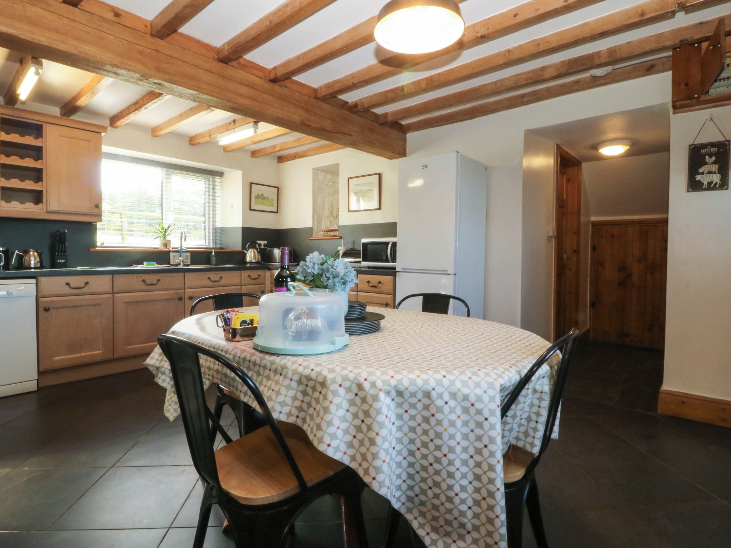 Una cocina con vigas de madera, una mesa de comedor con sillas y un refrigerador.