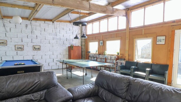 A room with a pool table, leather sofas, a ping pong table, and a bookshelf. - The Farmhouse (Lampeter)