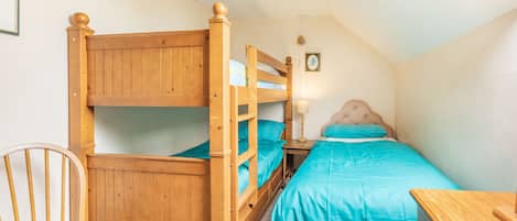 A bunk bed room with a wooden chair and a desk.