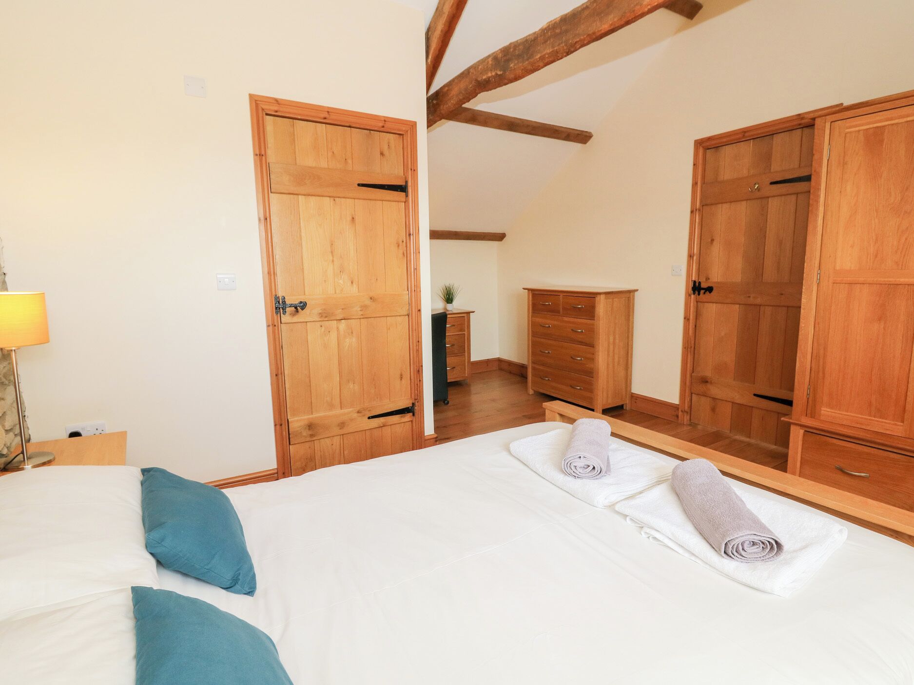 Une chambre à coucher comprenant un lit, deux armoires en bois, une commode et une lampe.
