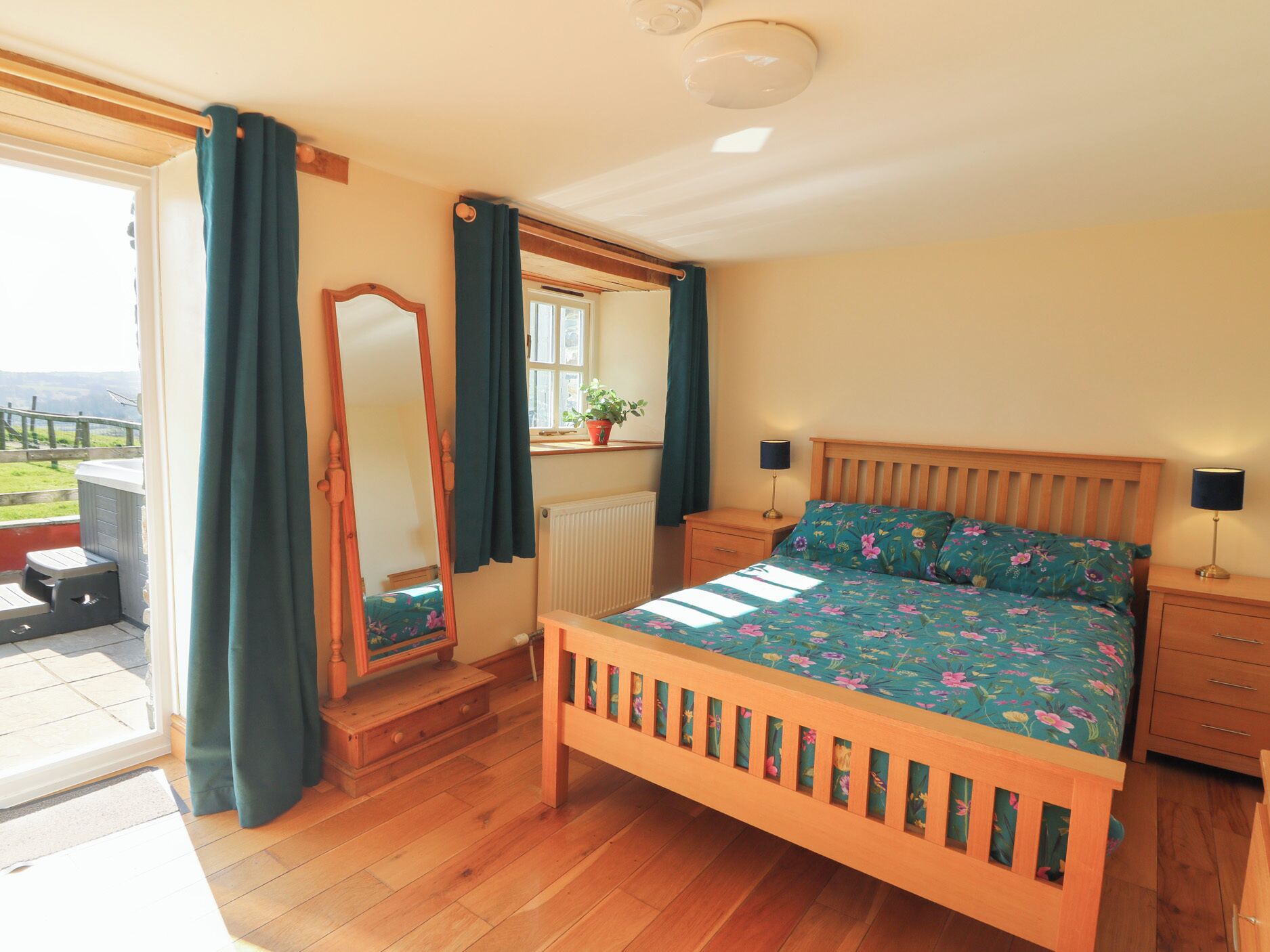 A bedroom with a wooden bed, a nightstand, a dresser, a mirror, and a window with curtains.