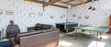 Una habitación con un sofá de cuero marrón, una mesa de billar y una mesa de ping pong.