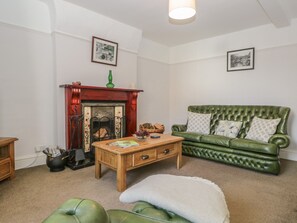 A living room with a green sofa, a wooden coffee table, a fireplace, and two framed pictures on the wall. - Hillside (Broughton in Furness)