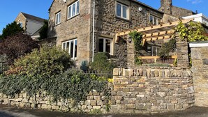 A stone house with a wooden porch and a stone wall. - The Shippon (Skipton)