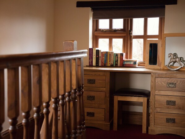 Ein Holztisch mit Fenster, einem Stuhl und einem Bücherregal voller Bücher.