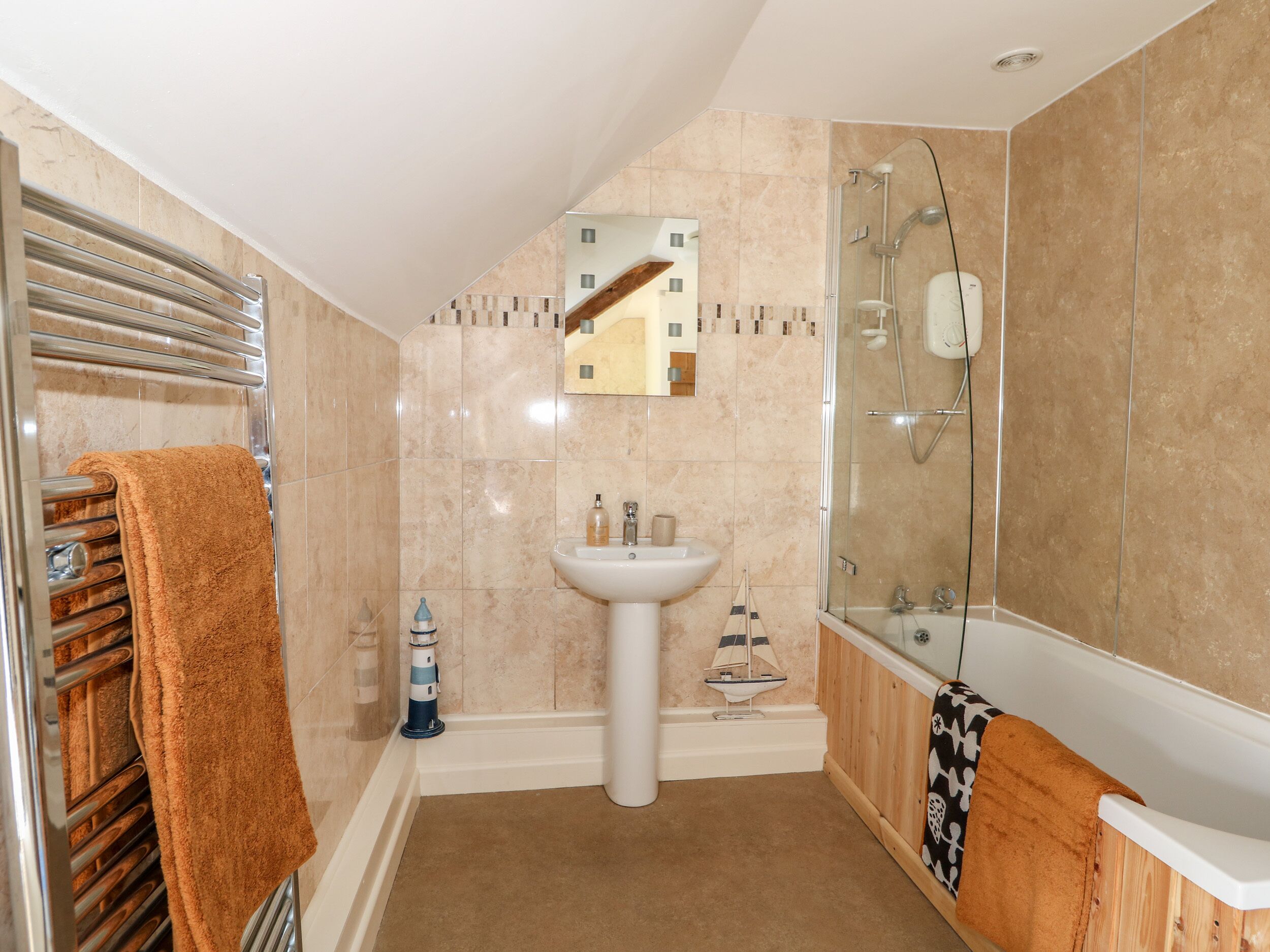 A bathroom with a glass-enclosed shower, a white sink, and a towel rack with a brown towel.
