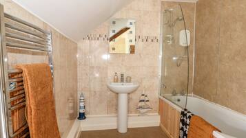 A bathroom with a glass-enclosed shower, a white sink, and a towel rack with a brown towel.