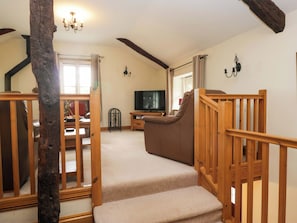 A staircase with wooden railings leading to a living area with a television and a sofa.