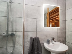A bathroom with a shower, a sink, a mirror, and a towel.