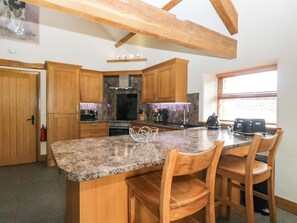 A kitchen with wooden cabinets, granite countertops, and a built-in island with chairs.