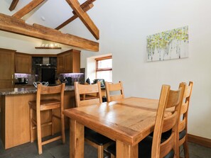 A kitchen with wooden cabinets, a dining table with chairs, and a painting on the wall.