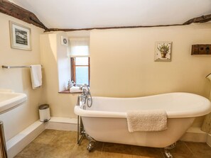 Une salle de bain avec une baignoire sur pieds, un lavabo et une fenêtre donnant sur un paysage agréable.