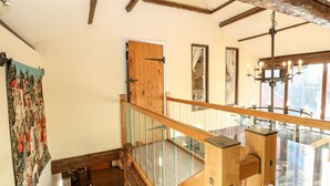 A wooden staircase with glass railings leading to a second floor. - The Barn (Thetford)