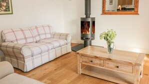 Una sala de estar con sofá, una mesa de centro de madera, chimenea y un espejo en la pared.