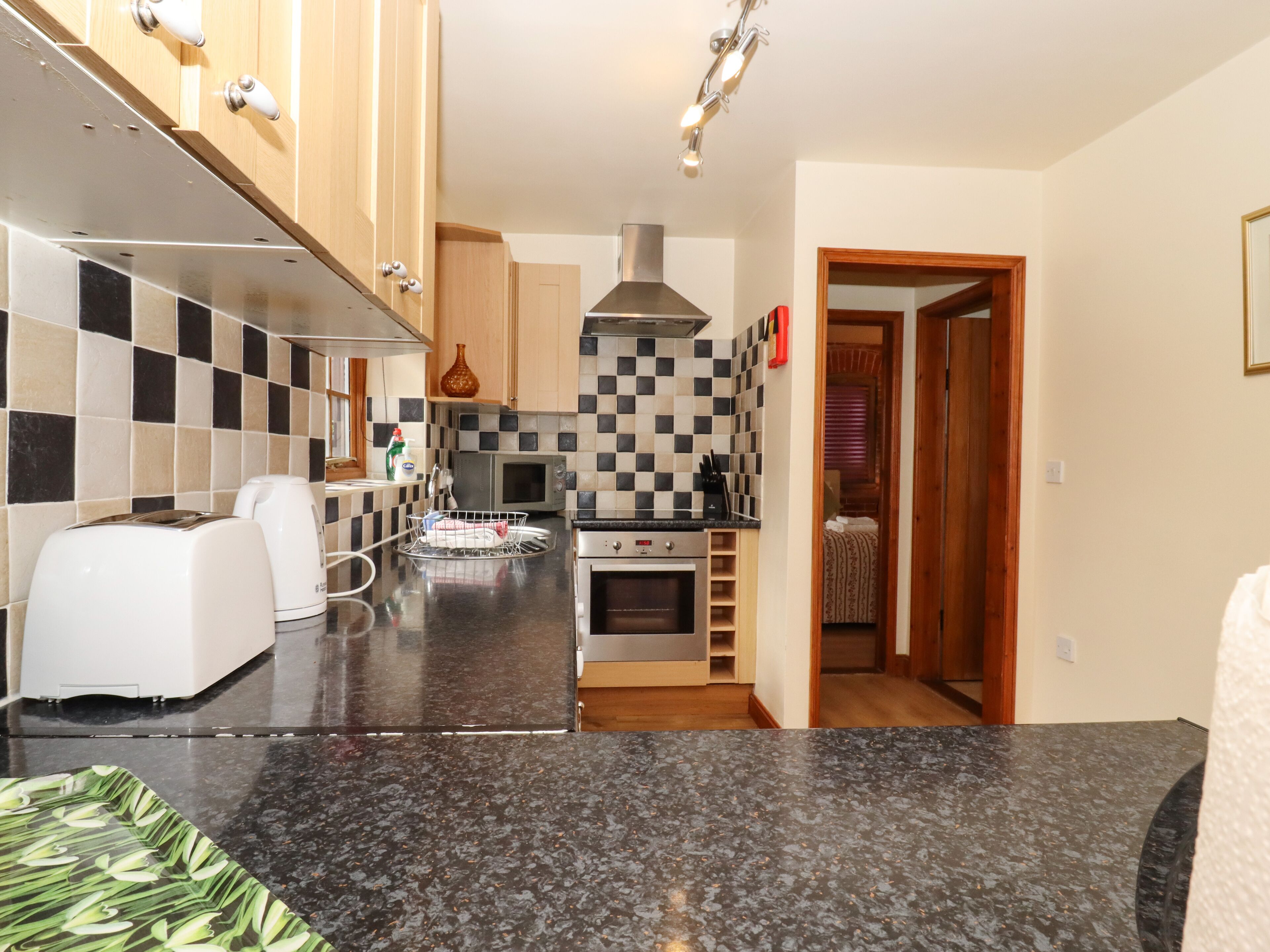 A compact kitchen with a microwave, toaster, and a sink.