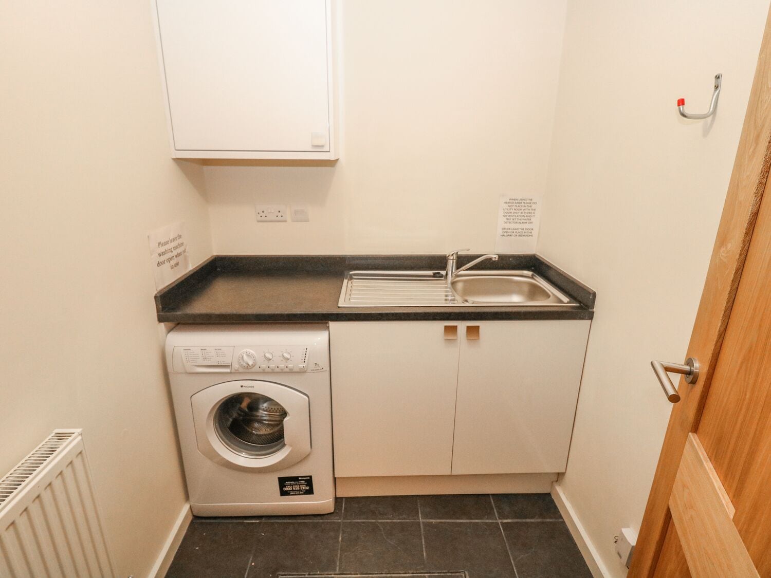 A compact laundry room with a washing machine, a sink, and a cabinet.