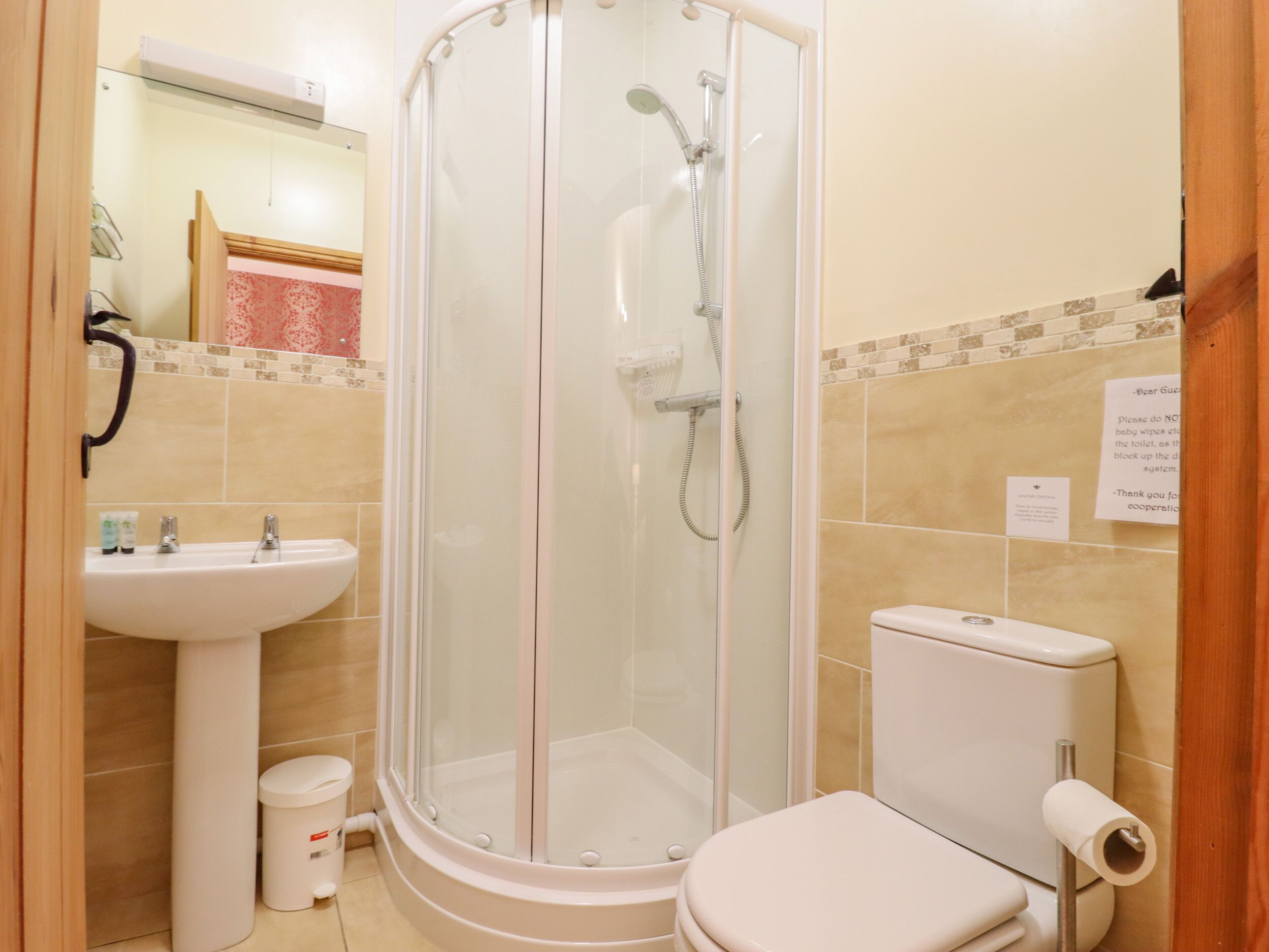A bathroom with a glass-enclosed shower, a sink, and a toilet.