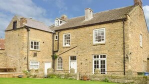 A stone building with multiple windows and a well-maintained lawn in front. - The Lodge (Scarborough)