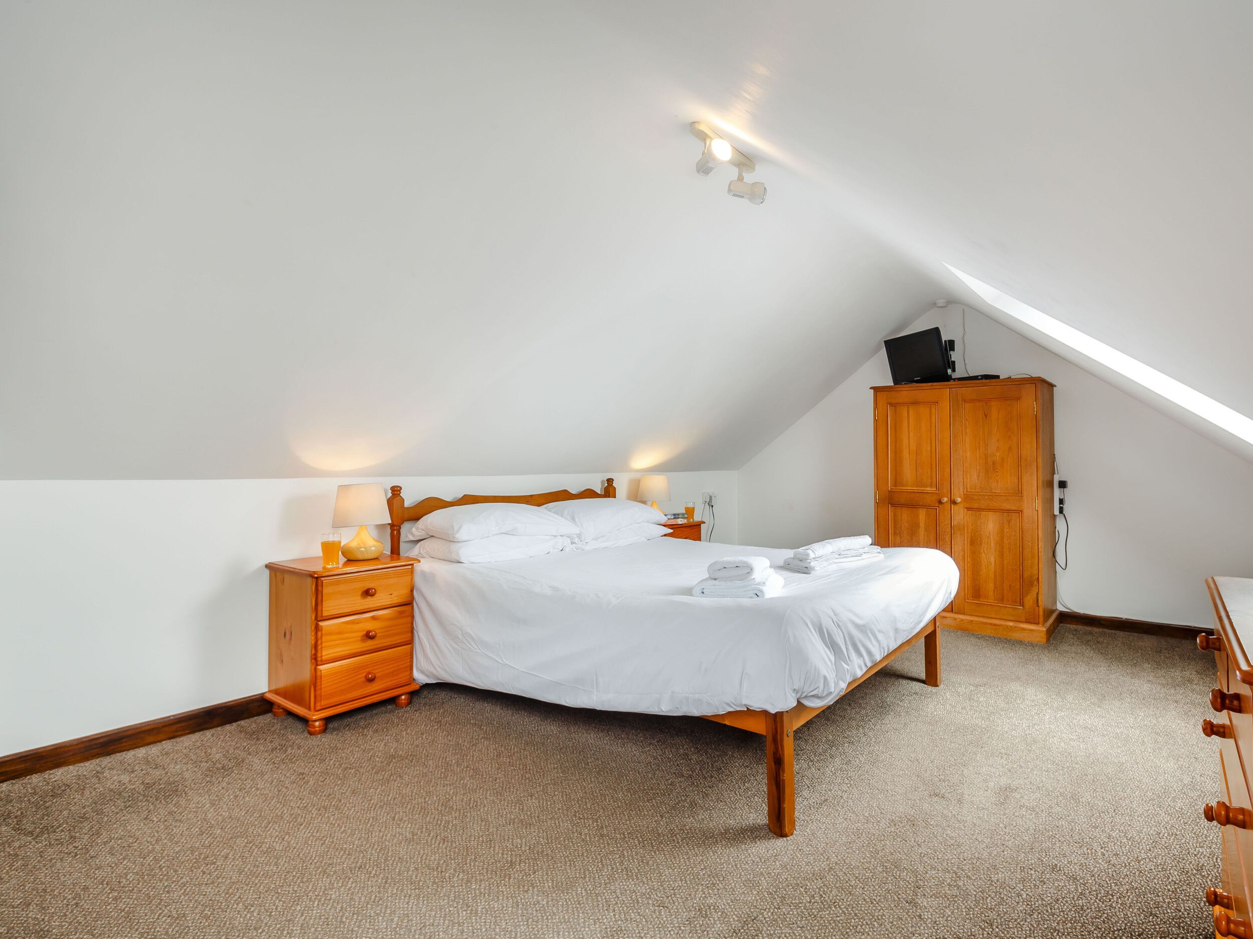 A bedroom with a bed, wooden nightstand, and a wardrobe.