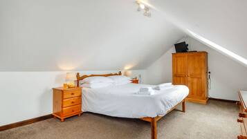 A bedroom with a bed, wooden nightstand, and a wardrobe.