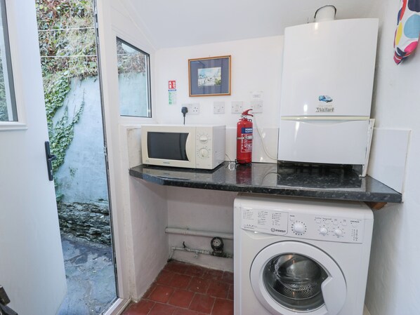Une petite buanderie équipée d’un lave-linge, d’un four à micro-ondes et d’un réfrigérateur.