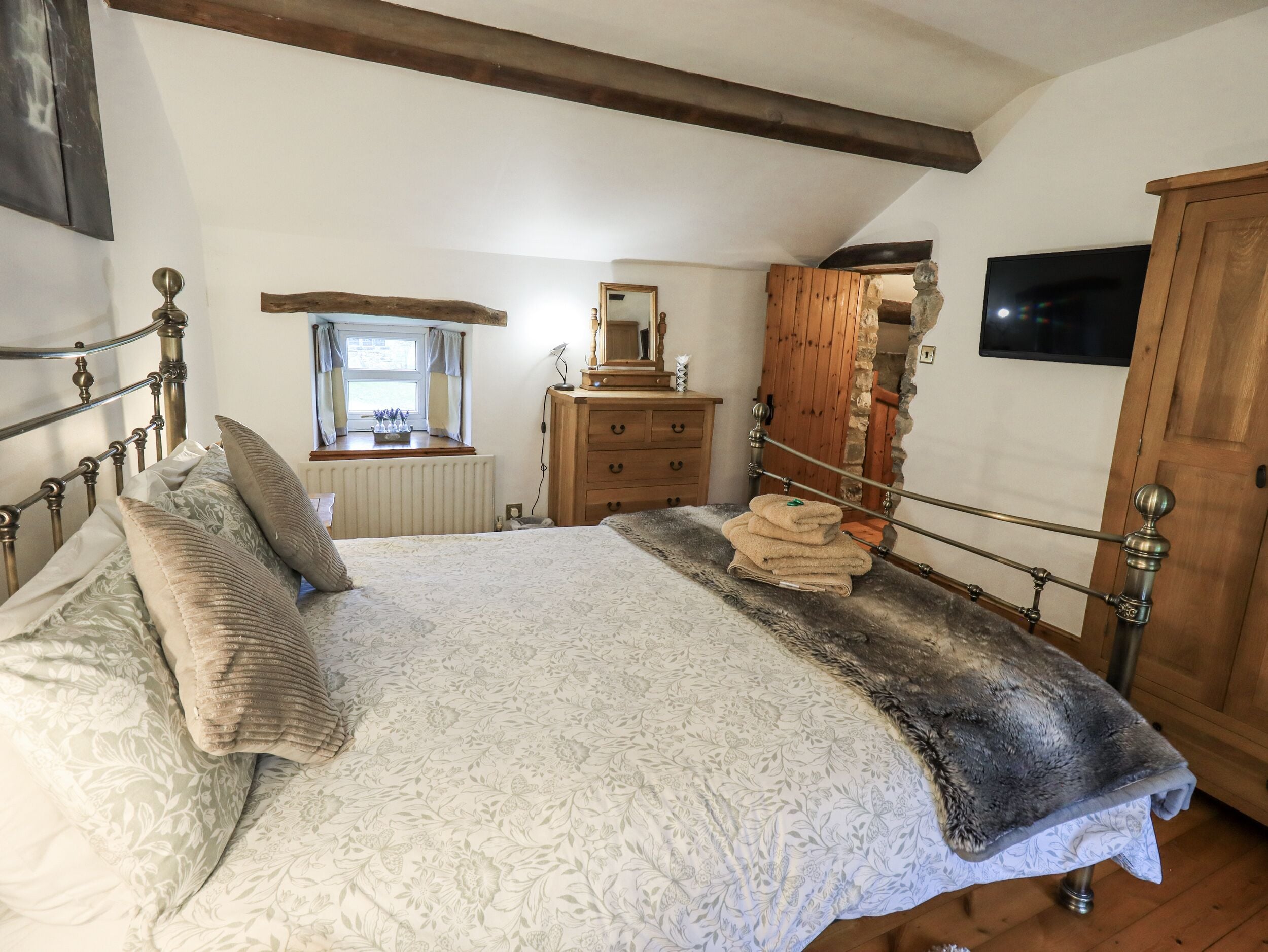 A bedroom with a bed, wooden dresser, and a mirror.