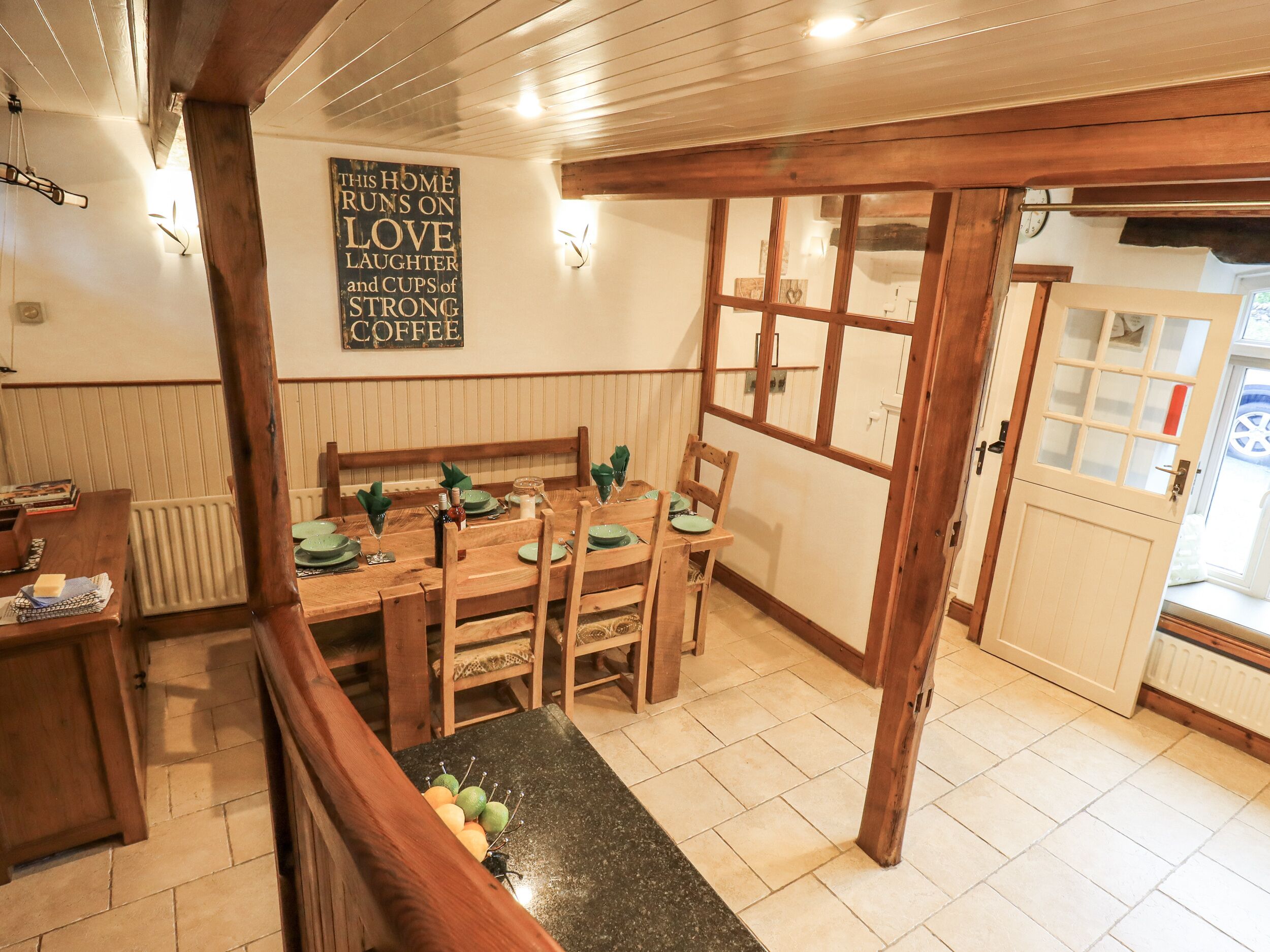 A cozy dining area with wooden furniture, a black countertop, and a wall sign.