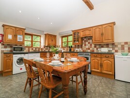 A kitchen with wooden cabinets, a dining table set for four, a washing machine, and a microwave.